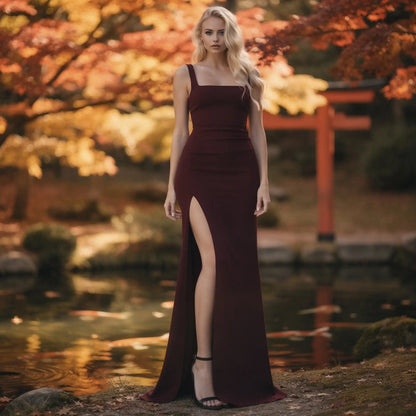 View of a fitted square neck maxi evening dress in deep burgundy, featuring a high slit and elegant fabric draping