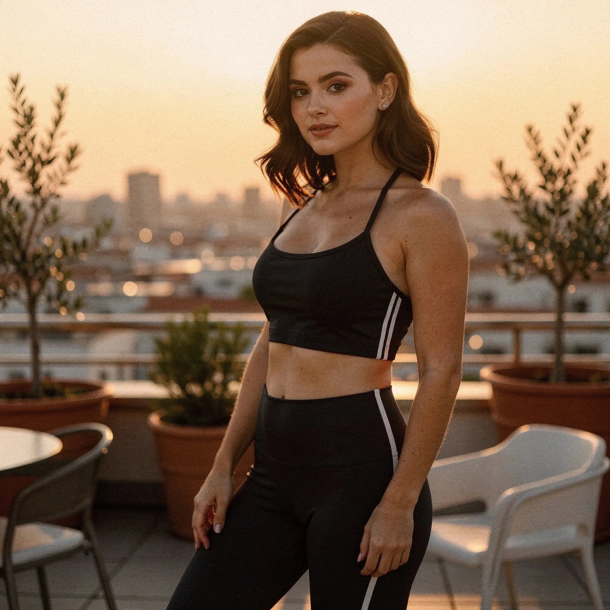 View of a relaxed fit backless sports bra in black, featuring adjustable straps and white stripes